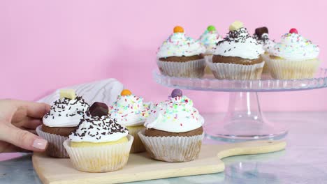 taking one cup cake with white cream from the table with served cup cakes for party