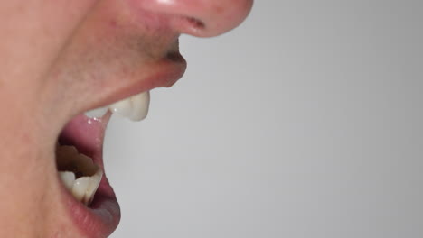 Close-up-side-view-of-an-angry-young-man-screaming-against-a-white-background