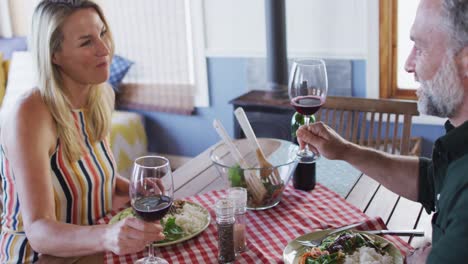 feliz pareja caucásica madura sonriendo, hablando y disfrutando de la comida juntos