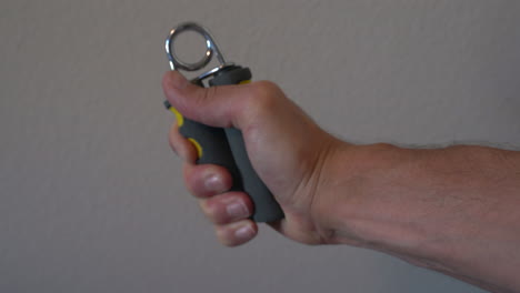 man working on his grip and forearm strength with a handgrip strengthener