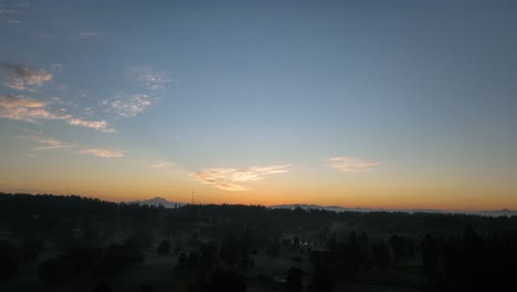 Panning-aerial-shot-of-the-sun-rising-over-Whidbey-Island's-Oak-Harbor-community-with-Mount-Baker-off-in-the-distance