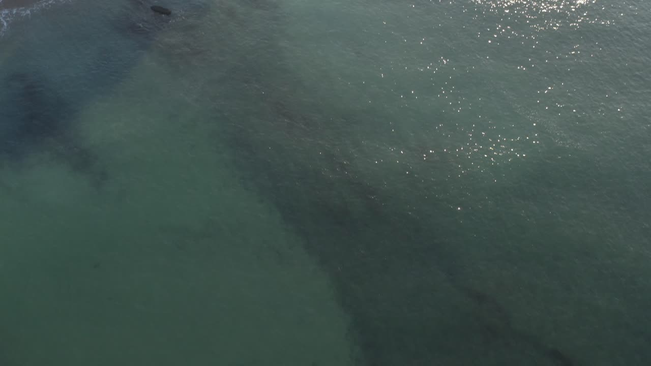 Drone flying over waters surface near beach, Saint-Jean-de-Luz, France. Aerial forward tilt-up reveal