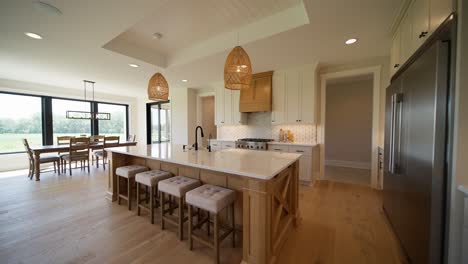 push-in shot of a spacious, bright kitchen with white countertops, cupboards, and light wood accents