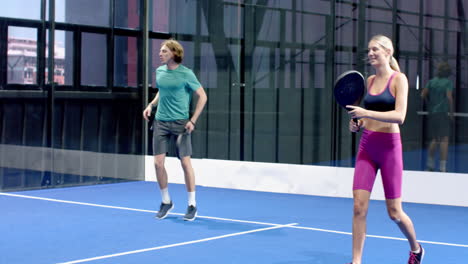 focused man playing padel tennis on blue indoor court, ready for action