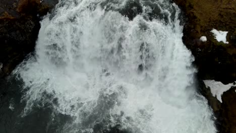 a closeup, 4k drone, aerial, cinematic, and unique shot of rapid cascading waterfalls in the middle of a rocky mountain in iceland