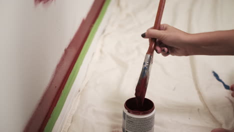 young woman paints red wall in house