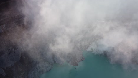 aerial drone shot looking down through the sulfuric gases of mount ijen in east java, indonesia