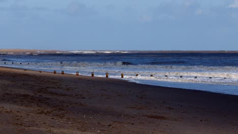 cloud-shadows-rolling-onto-Skegness-sandy-beach-with-groynes-on-the-horizon