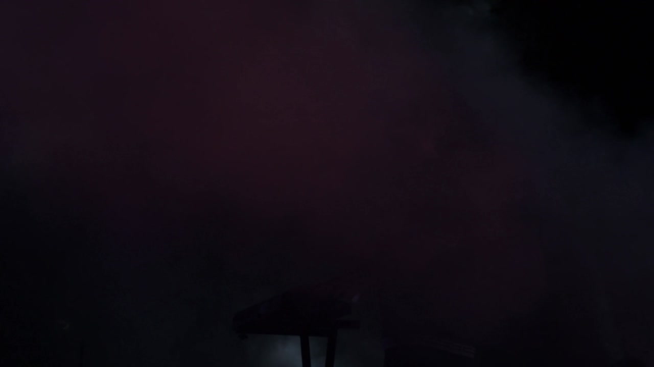 silueta de un tecladista entre el humo y las luces en un concierto