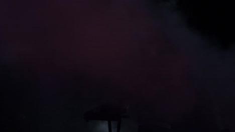 silhouet van een toetsenist tussen rook en lichten in een concert