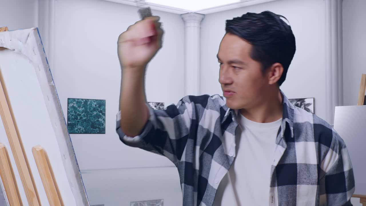 갤러리에서 오일 페인트와 브러쉬로 캔버스에 그림을 그린 아시아 남성 예술가의 클로즈업