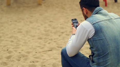 Mann-Sitzt-Auf-Spielplatz-Und-Benutzt-Smartphone.-Mann-Lifestyle-Mit-Smartphone