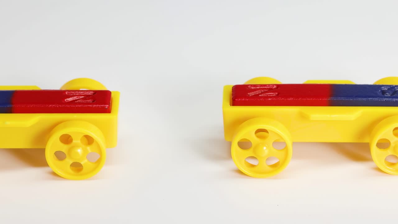 Close-up of hands manipulating yellow toy cars with red and blue tops on a white surface.