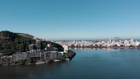 Panorámica-Aérea-Lenta-Alrededor-De-La-Ciudad-Lagoa-Rodrigo-De-Freitas-En-Río-De-Janeiro-Revelando-Tres-Montañas-A-Partir-Del-Barrio-De-Ipanema