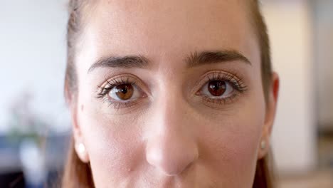 retrato de una feliz mujer de negocios caucásica abriendo los ojos marrones en la oficina en cámara lenta