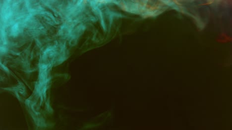gotas de pintura coloridas mezclándose en el agua. tinta lisa girando y salpicando desde arriba bajo el agua. nube de tinta aislada en fondo negro. explosión de humo abstracto de color