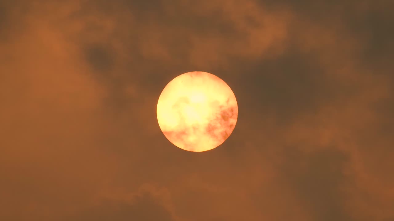 disparo de cerca del sol cubierto por oscuras nubes de humo contaminadas, cielo nublado naranja
