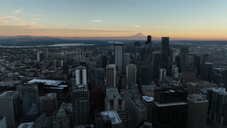 aerial pan across seattle cityscape at dusk with mount rainer on the horizon