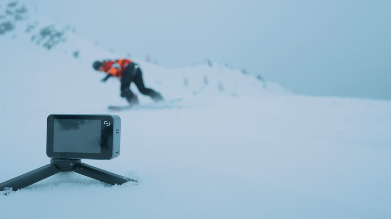 Smal action cam capturing a snowboarder.
