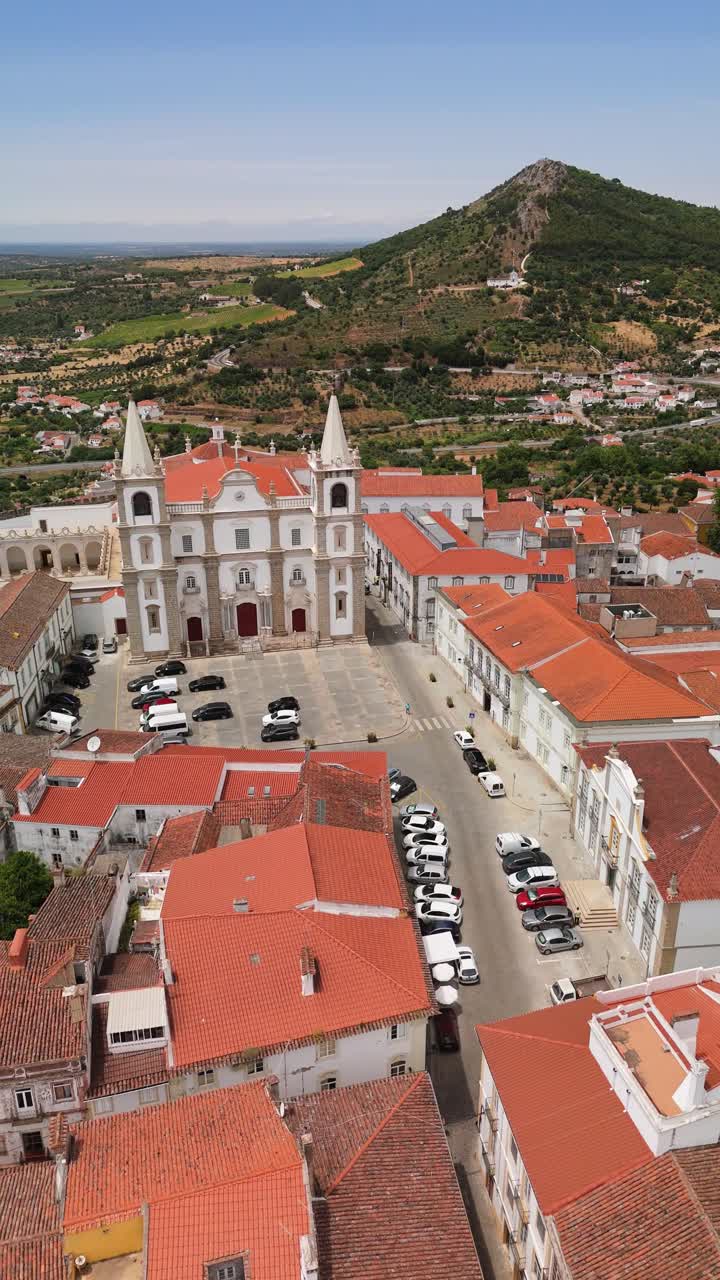 Drone flyover Portalegre Cathedral over red-roof city, Serra de São Mamede backdrop