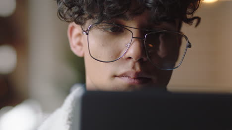 close up attractive young man student using tablet computer in cafe browsing online reading social media messages enjoying relaxing entertainment wearing stylish glasses