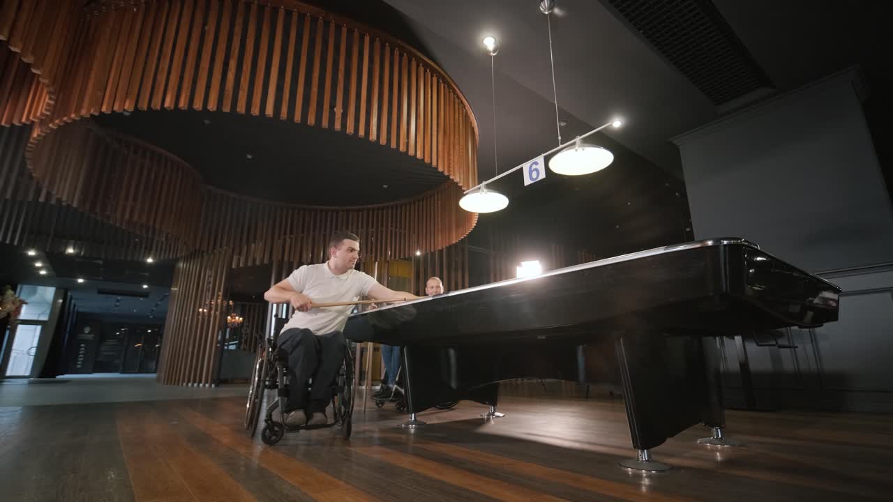 체어에 앉아 있는 장애인 성인 남성들이 클럽에서 빌리어드를 치고 있습니다.