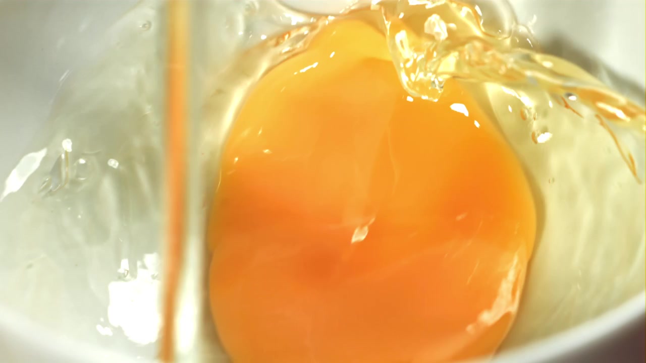 Slow Motion of a Raw Egg Yolk and White Pouring into a Bowl