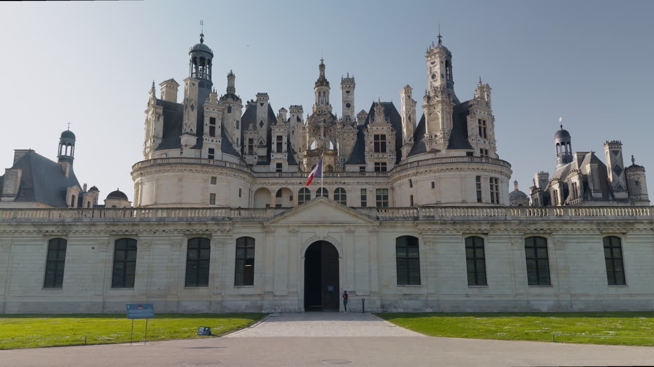 Majestic French castle with Renaissance towers, tourists, and clear sunny skies