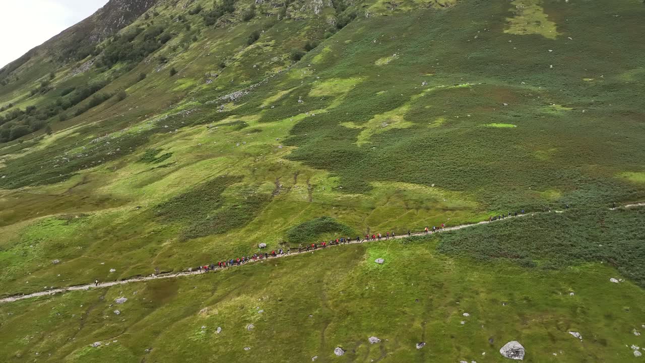 toma aérea de un grupo de senderistas caminando por el camino que conduce a la montaña ben nevis