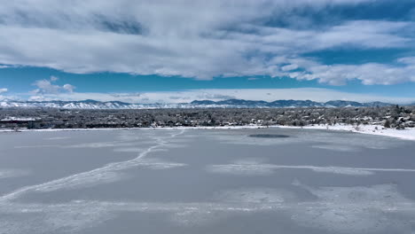 rising aerial of denver's sloan lake frozen over revealing residential housing covered in snow