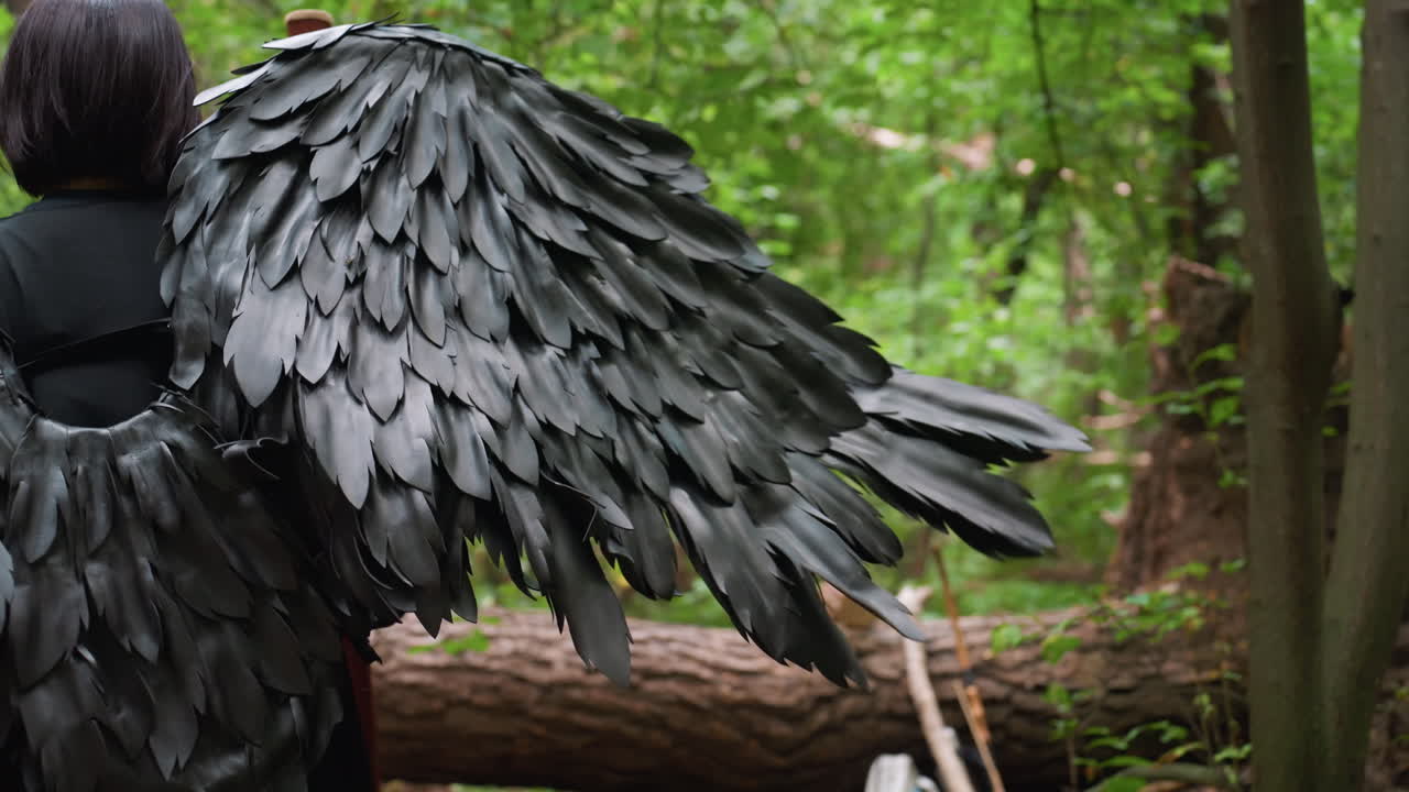 Close up back view of black fairy walking through lush forest toward fallen log, showcasing dark detailed wings glowing under soft light, creating mystical fantasy atmosphere