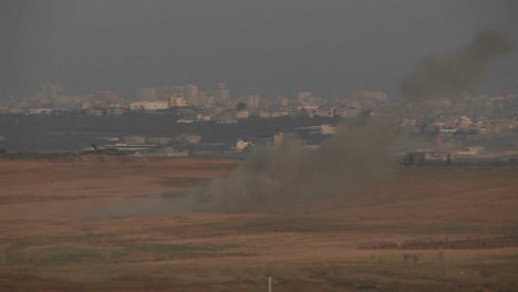 smoke rises in the distance between israel and the gaza strip