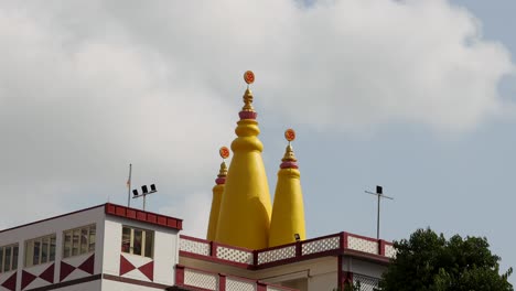 a group of tourists takes photos of the colorful lakshminarayan temple from a lively outdoor plaza, under bright daylight with steady camera movement