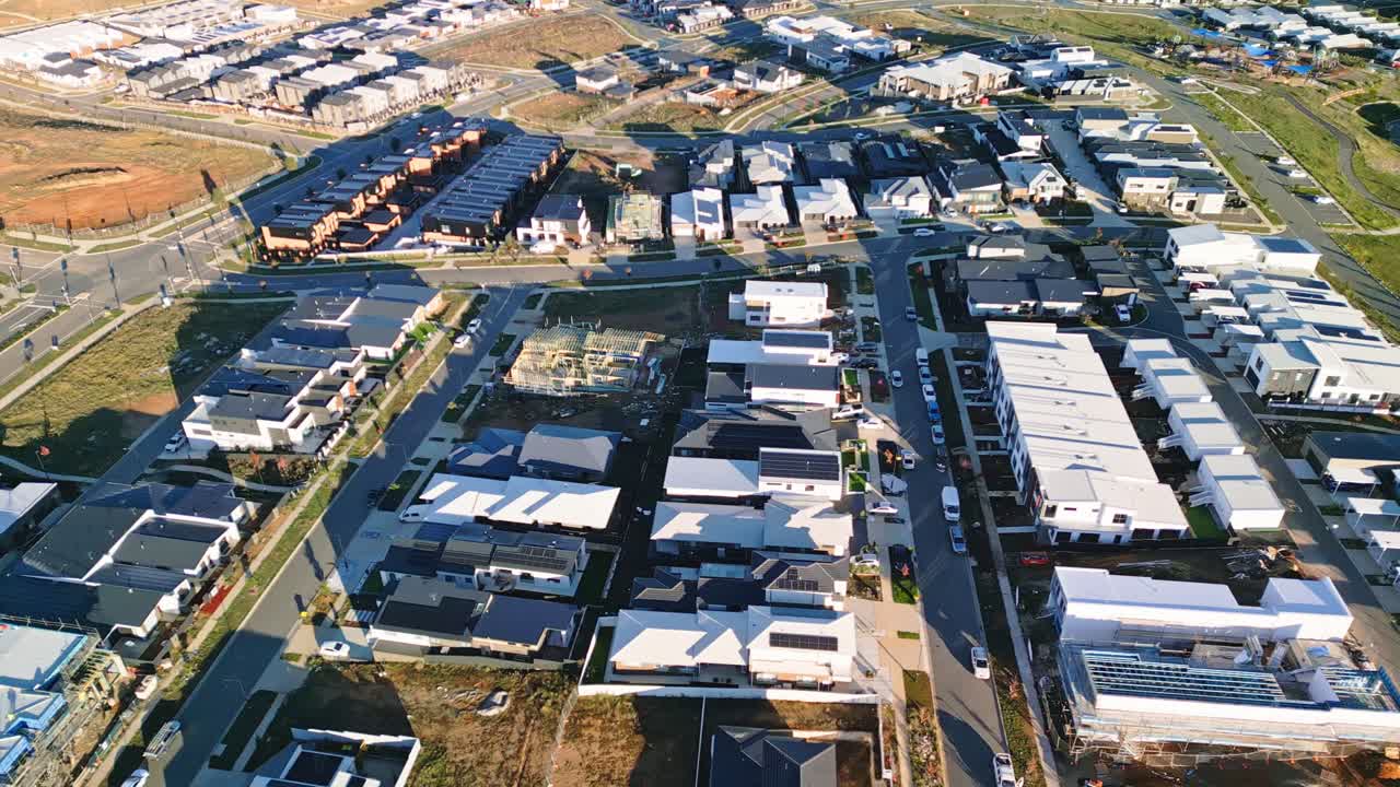 Drone footage flying over a partially built house in a new Canberra suburb, surrounded by completed homes.