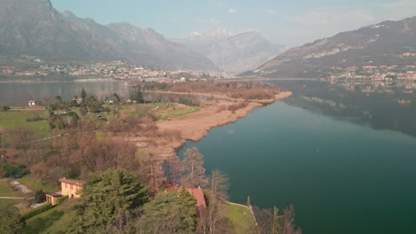 Calm-Water-Of-Lake-With-Reflections-Of-Sky-And-Mountains-At-Daytime-On-A-Sunny-Spring-Day