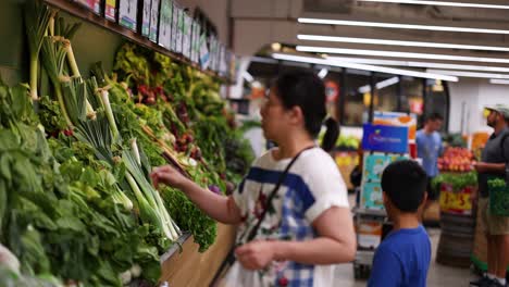 mother and son selecting vegetables at supermarket