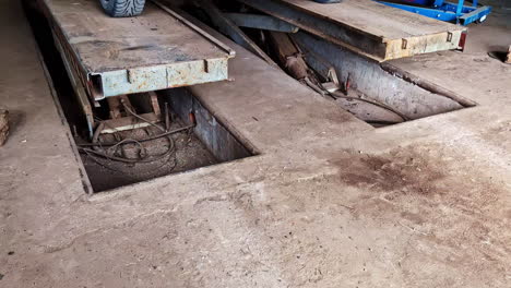 hydraulic scissor lift platform lifts up with open pits in gritty auto workshop interior
