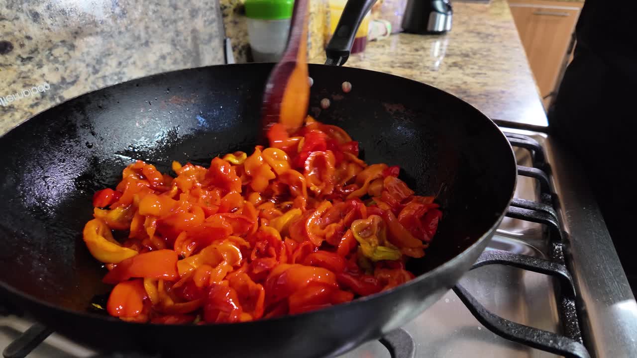 Mescolare peperoncini rossi con spatola di legno in padella
