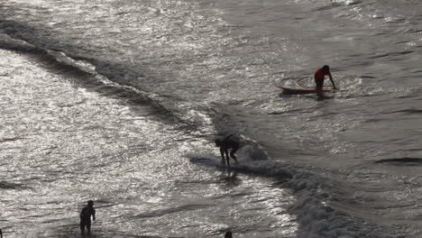 Cámara-Lenta-De-Surfistas-Practicando-En-Pequeñas-Olas-Disparadas-En-Silueta