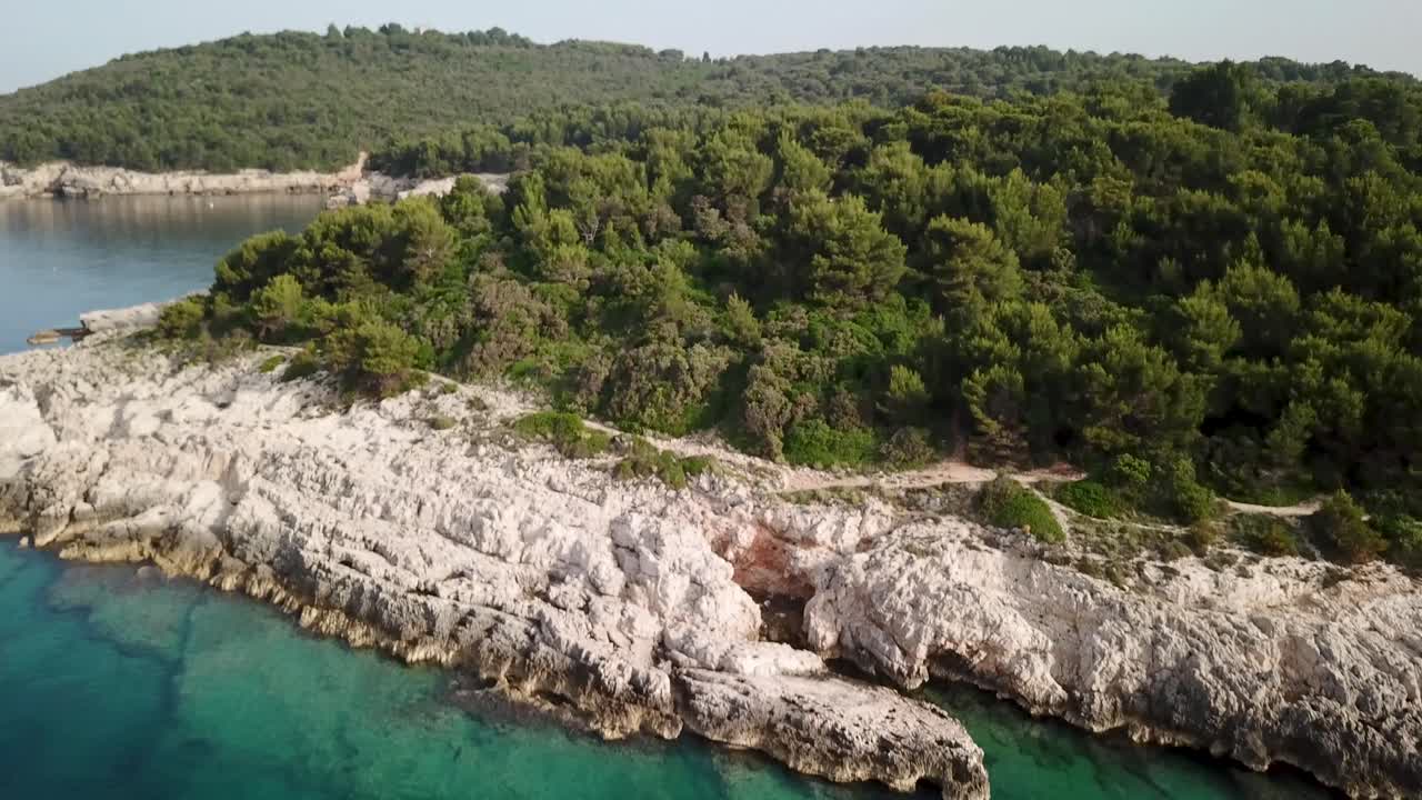 Vista aérea ascendiendo sobre la costa rocosa de Croacia y hacia los árboles.