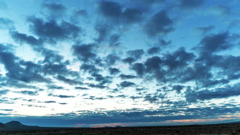 fast moving clouds cross the sky above the mojave desert landscape as the sun rises - time lapse