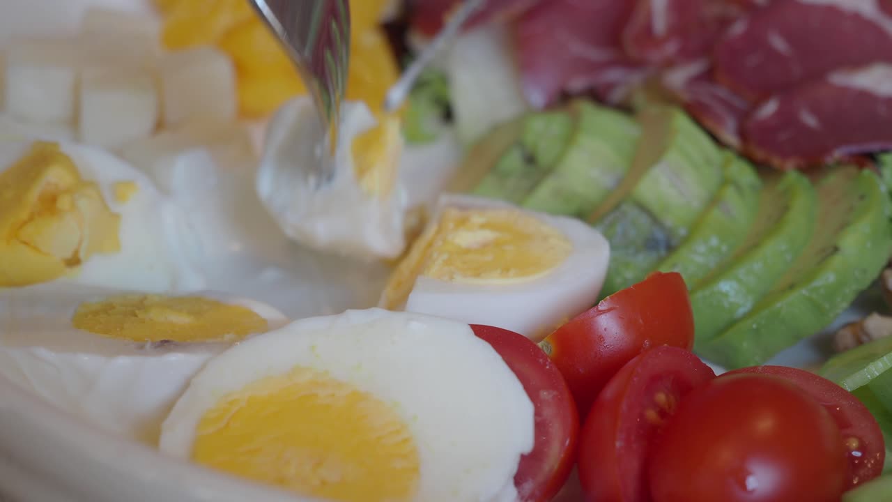 Close-up of a diverse breakfast platter with eggs, avocado, and deli meats