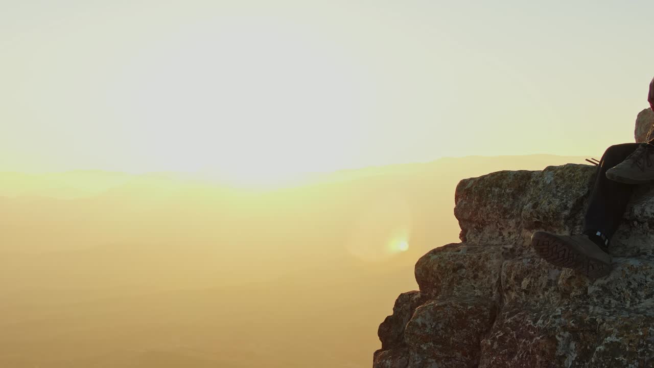 공중에서 볼 수 있는 광경: 남자가 앉아 있는 바위와 해가 지는 에 쓸린 계곡을 따라 날아다니며 밝은 렌즈를 만든다.