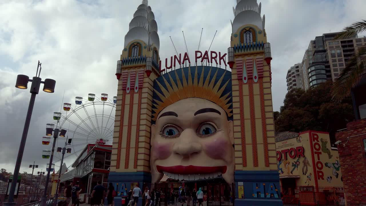 Luna Park main face entrance in the northern shore full of people on an overcast day, Stable walking back handheld shot