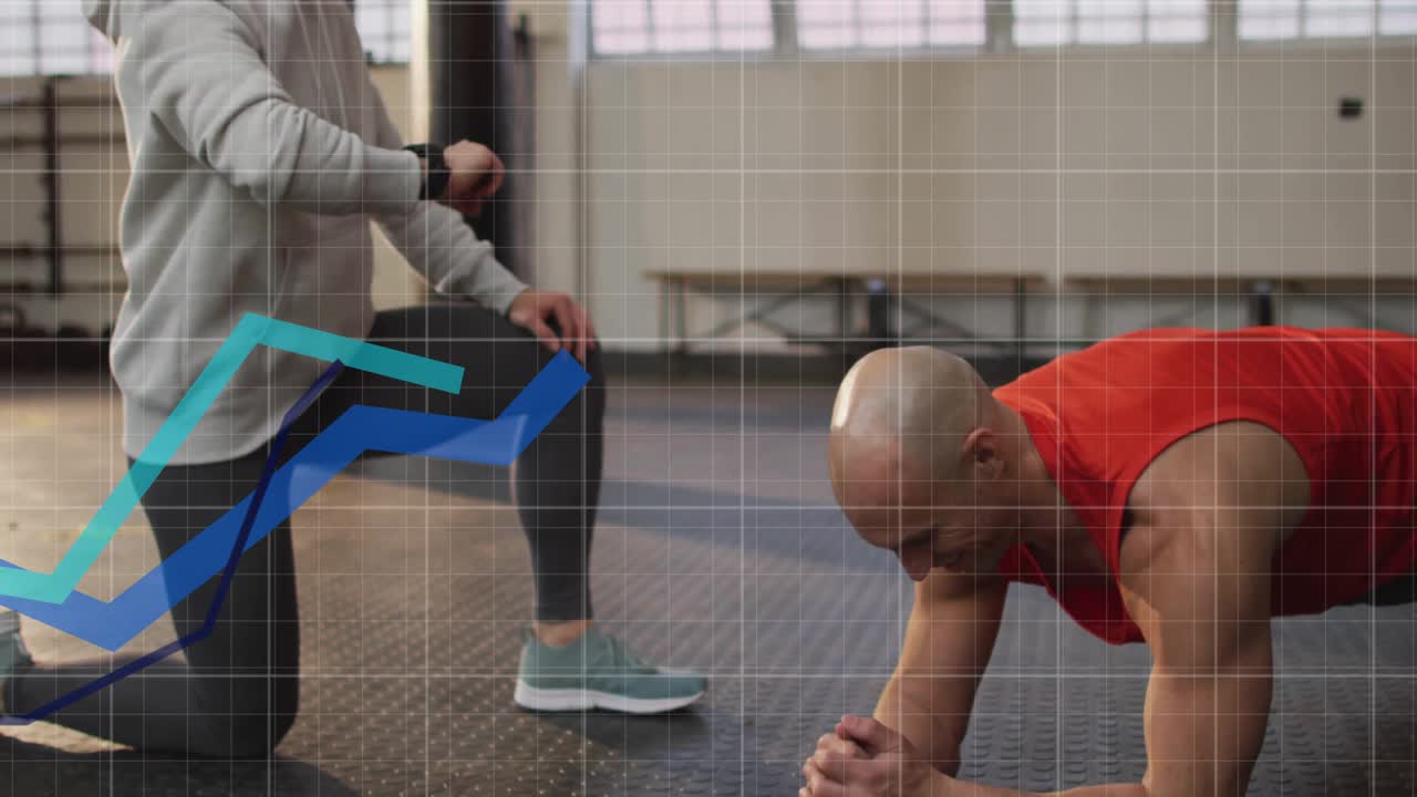 Trainer überprüft Smartwatch und startet Fitnessgrafiken, während ein Athlet einen Unterarmstütz auf der Gymnastikmatte hält.