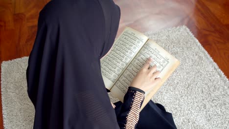 young muslim female wearing islamic clothes reading the quran