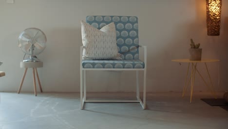 modern minimalist chair with blue pillow and fan in a room