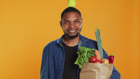 Young-adult-trying-to-keep-balance-with-an-apple-on-his-head-in-studio