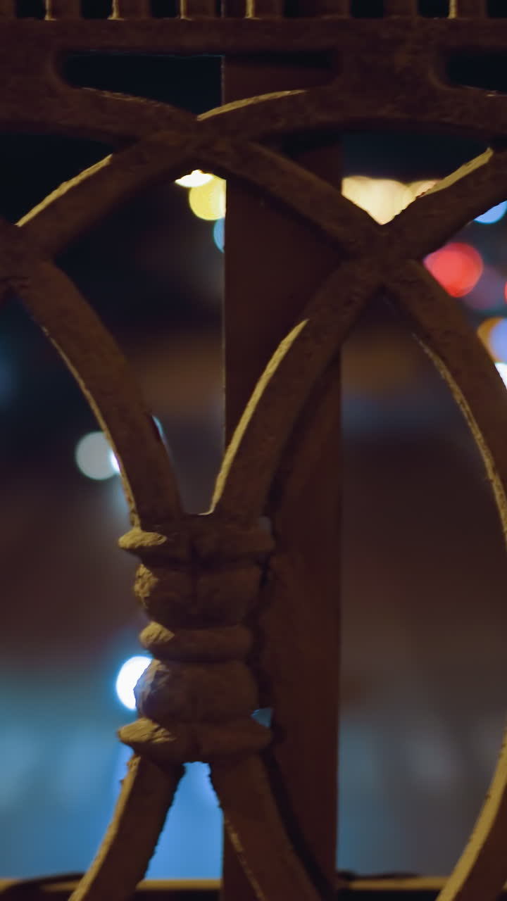 밤에는 도시 불빛과 자동차 헤드라이트의 보케 효과가 있는 장식적인 철 울타리의 근접 시각