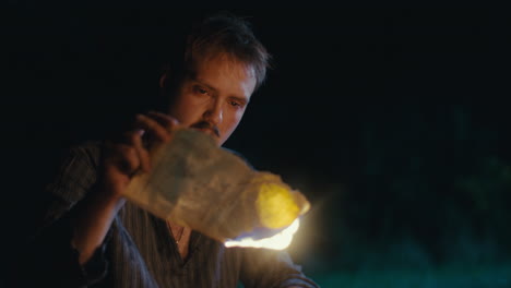 man burning a document at night